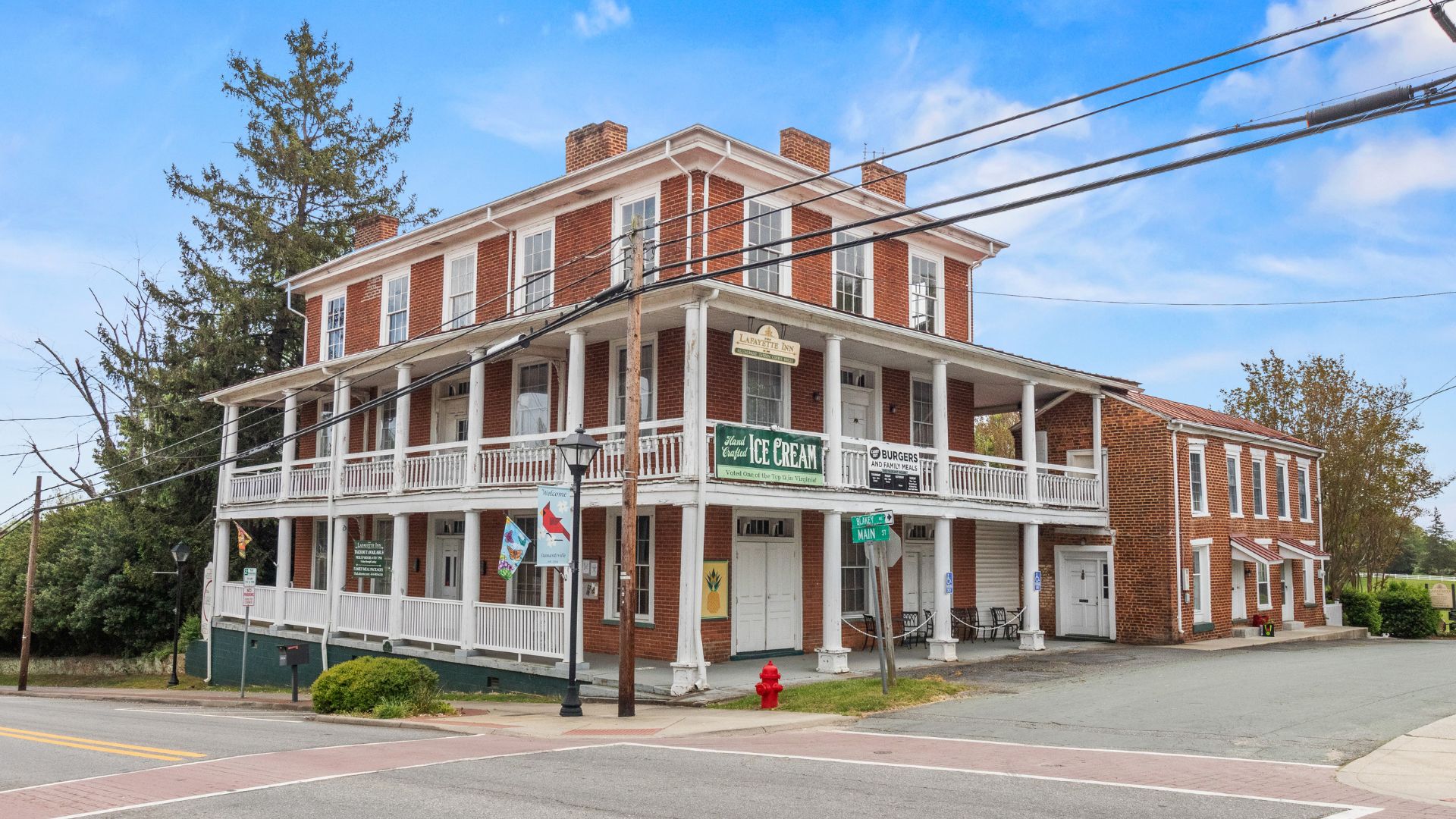 Large red brick two story inn with wrap around porches and columns