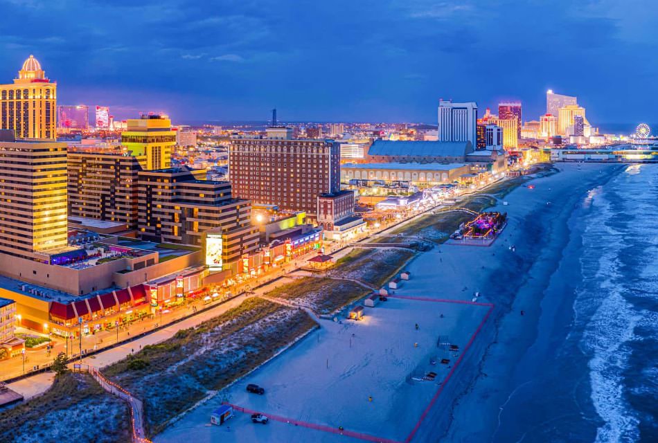 A row of large hotel buildings by a shoreline lit up at night